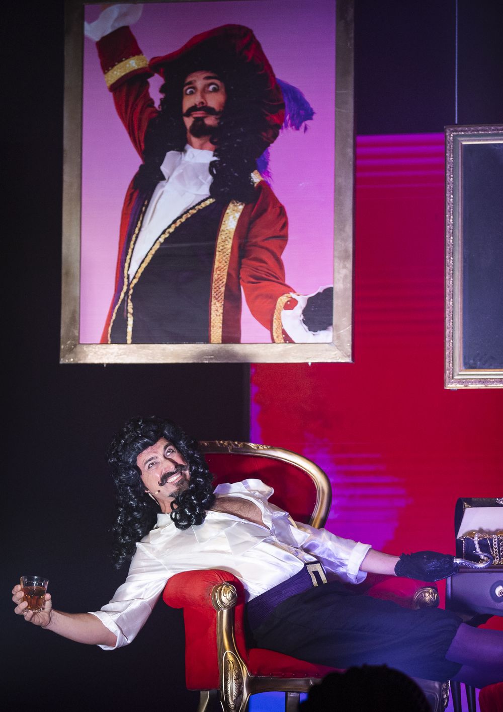 Captain Hook lounging in a red chair beneath his own portrait, Zealous Productions' Peter Pan pantomime, December 2022