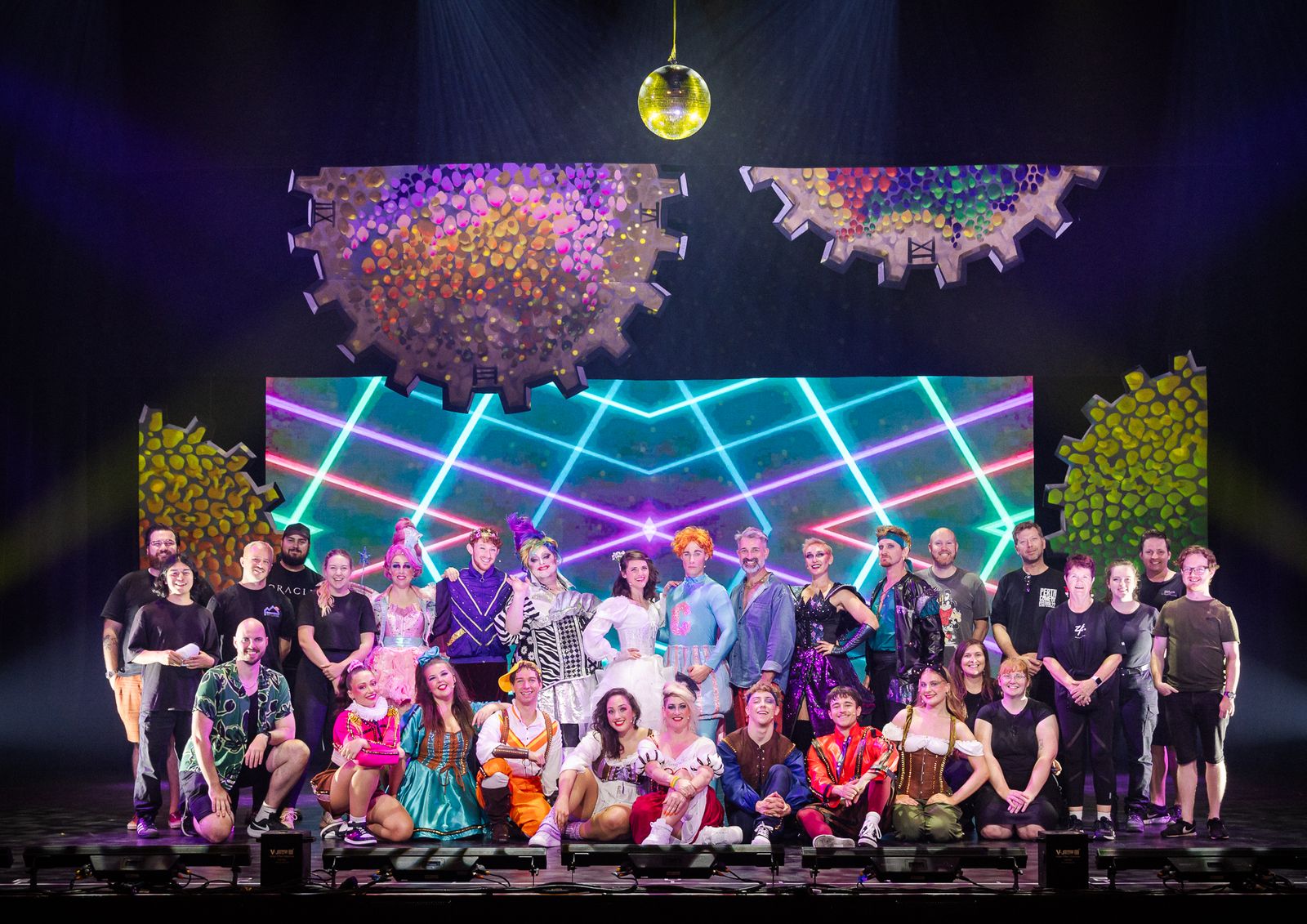 The Sleeping Beauty company posing on stage under a 1980s-style neon set, Zealous Productions Christmas pantomime, December 2023