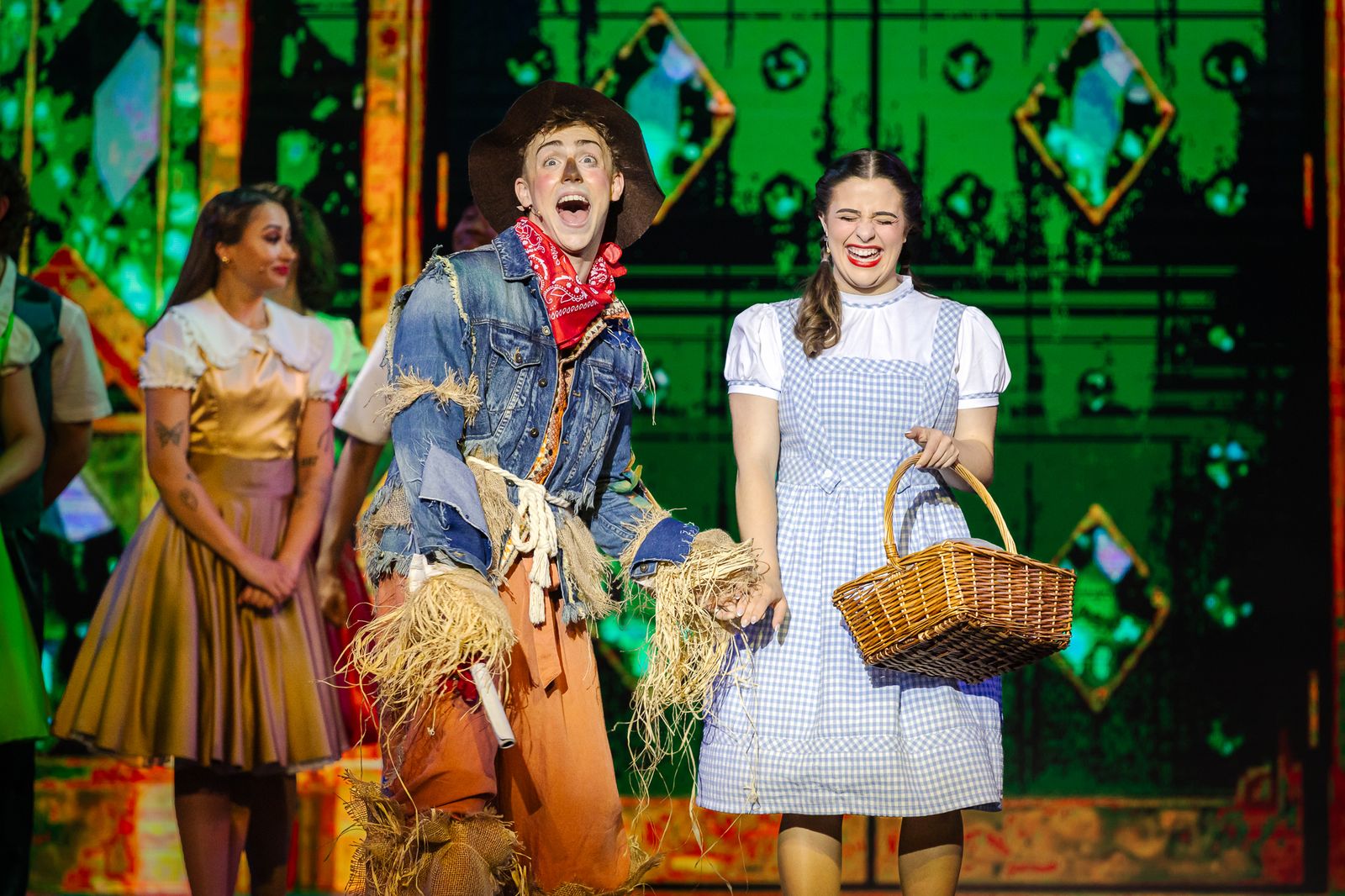 Dorothy and the Scarecrow arm in arm in a bright green set, The Wizard of Oz pantomime by Zealous Productions, December 2025